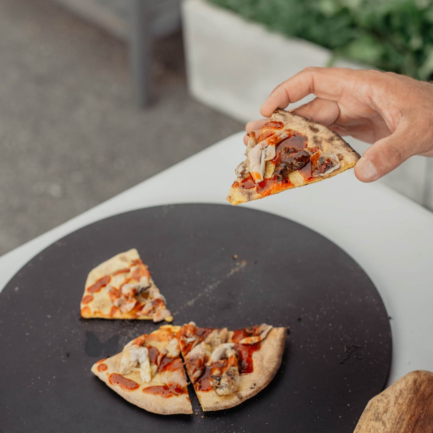 Man picks up a slice of flatbread covered in scotch bonnet hot sauce